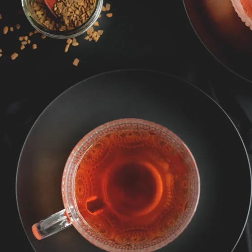 cinnamon ginger herbal tea in a glass mug with cinnamon chips scattered