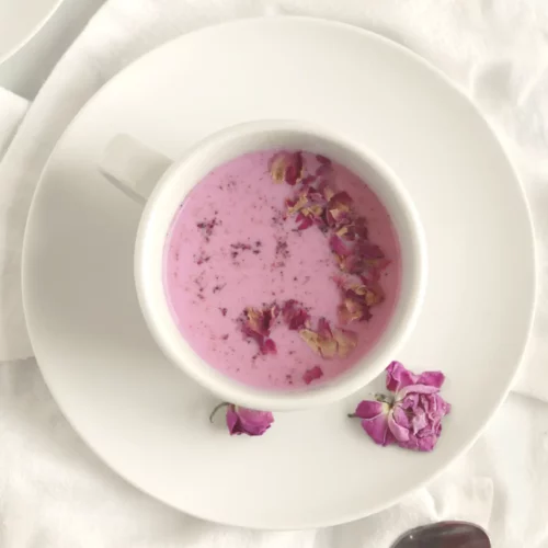 Rose milk in a white mug with rose petal garnish