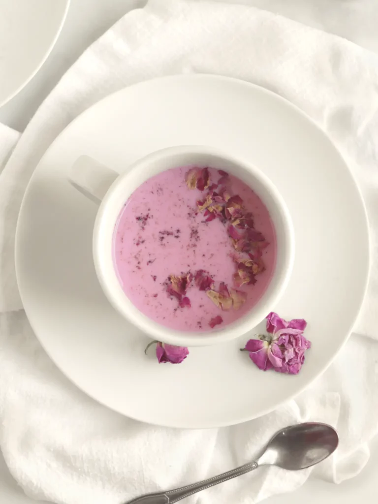 Rose milk in a white mug with rose petal garnish