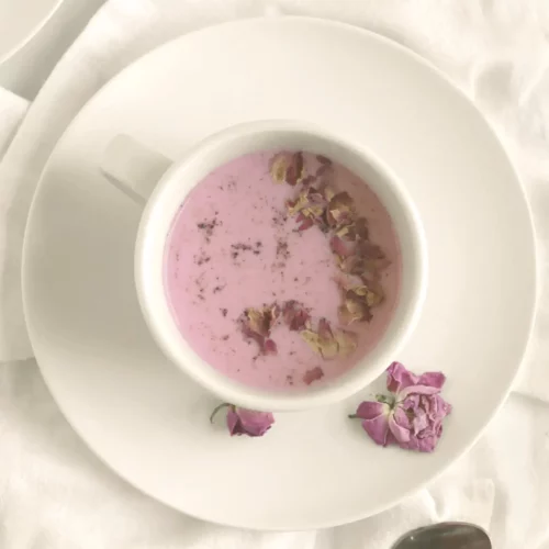 Rose milk in a white mug with rose petal garnish