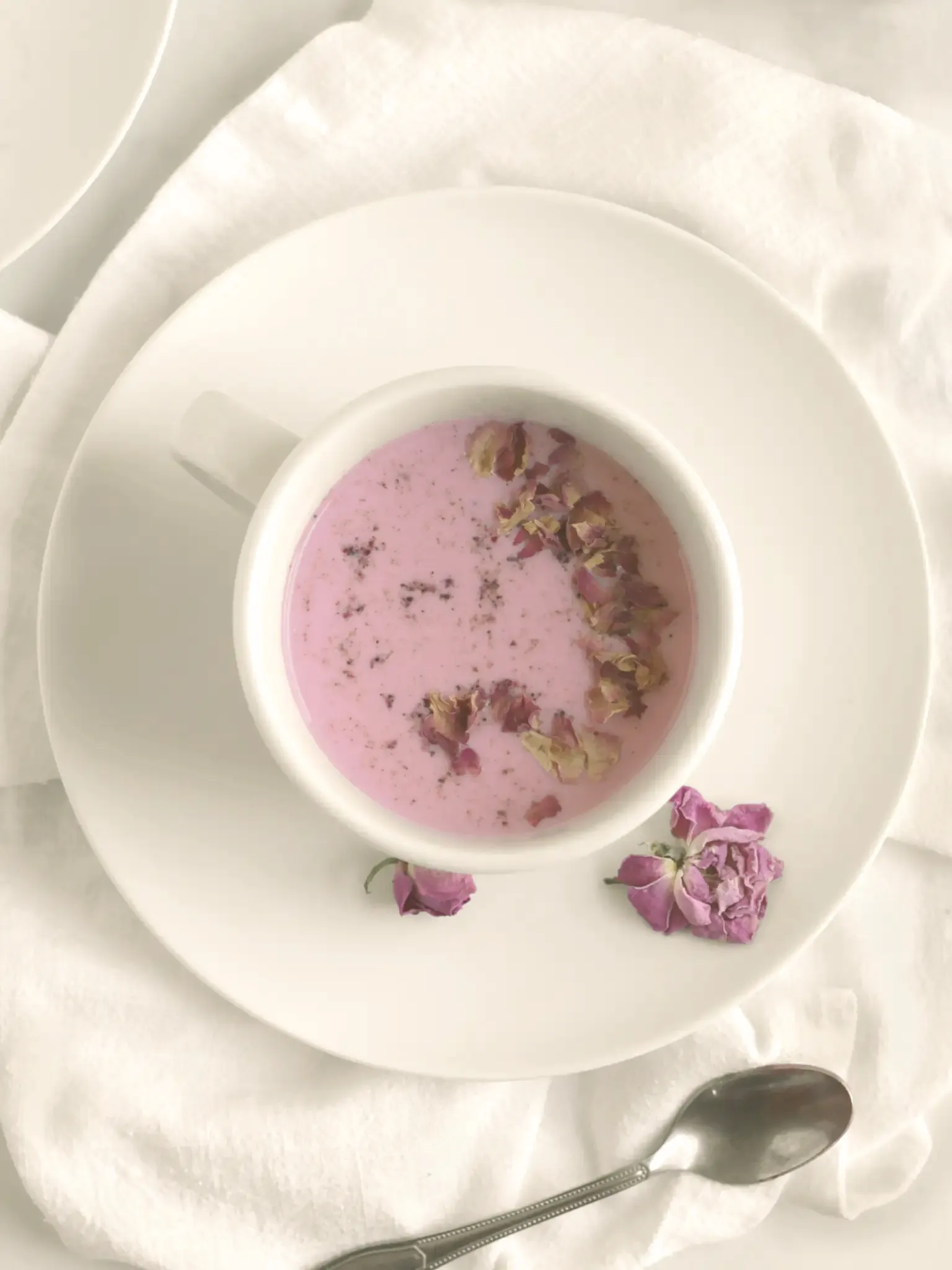 Rose milk in a white mug with rose petal garnish