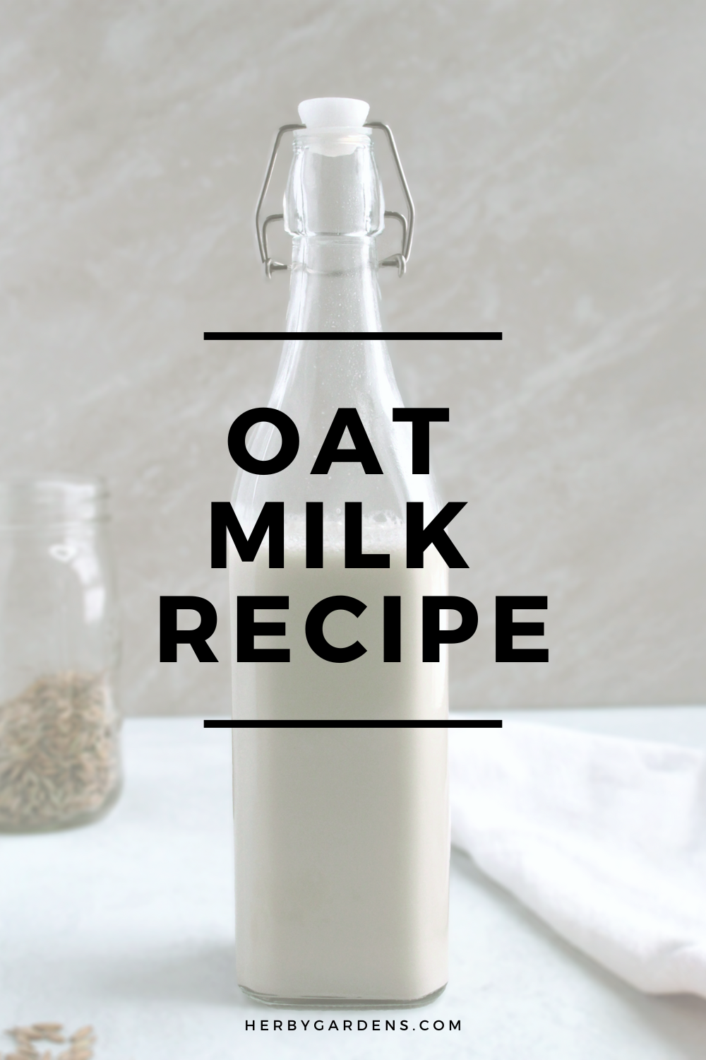 Oat milk in a glass bottle on a table. The words "Oat Milk Recipe" are written as an overlay. Used for Pinterest pins.