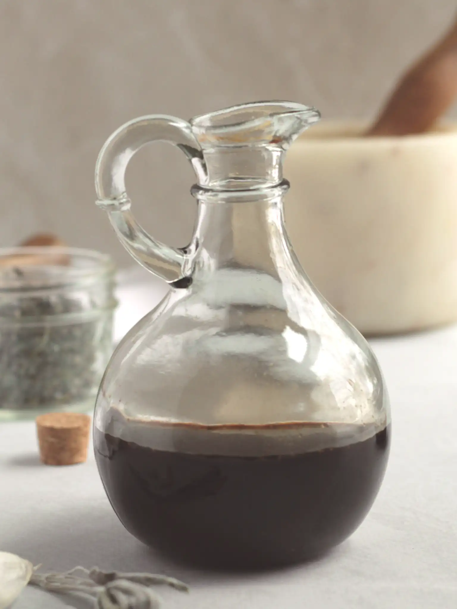 Garden herb balsamic vinegar in a glass vinegar jar on a counter.