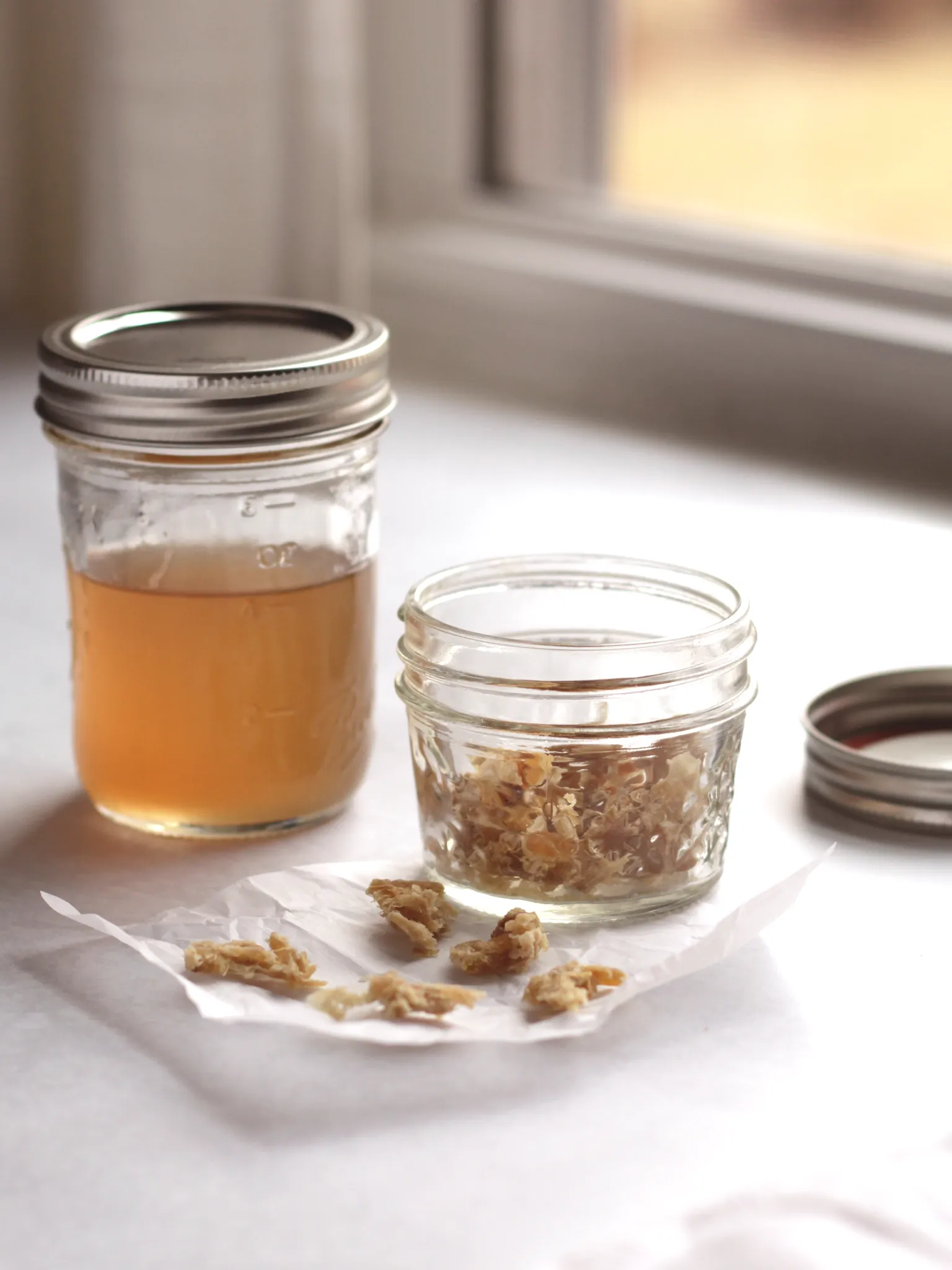 Ginger syrup in a mason jar next to a jar of crystallized ginger.