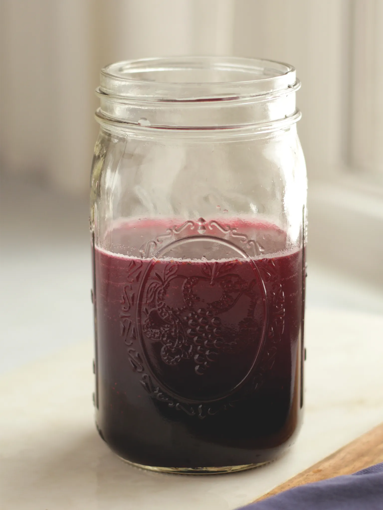 A Mason jar holding the finished blueberry lavender shrub with white wine vinegar