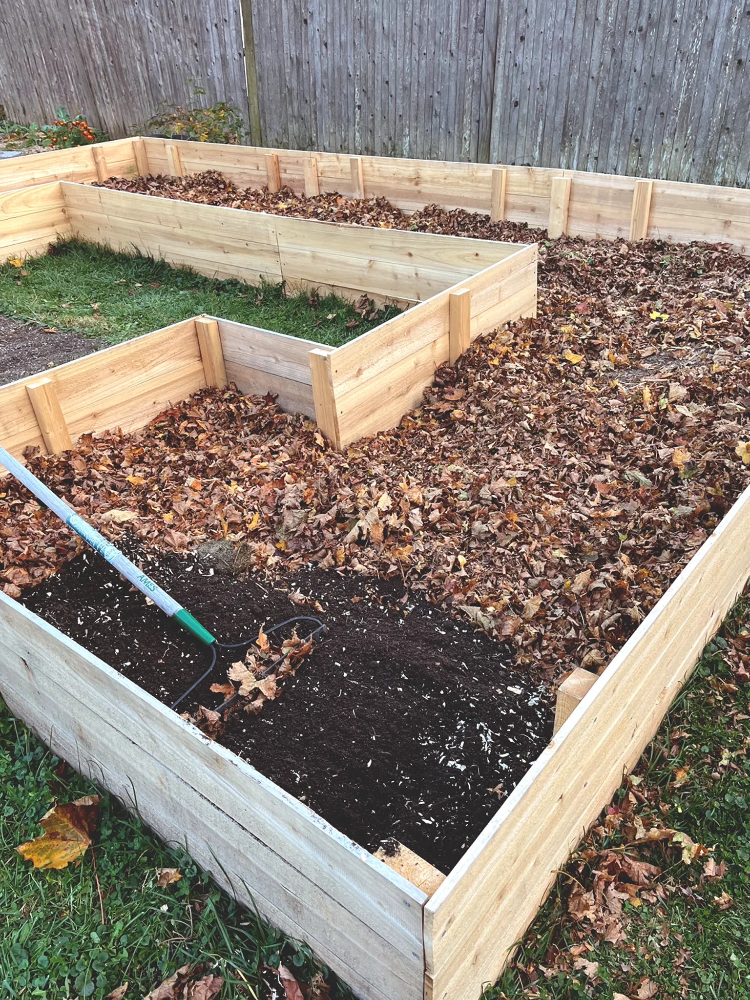 Side-view of new raised bed filled halfway with leaves and soil. 