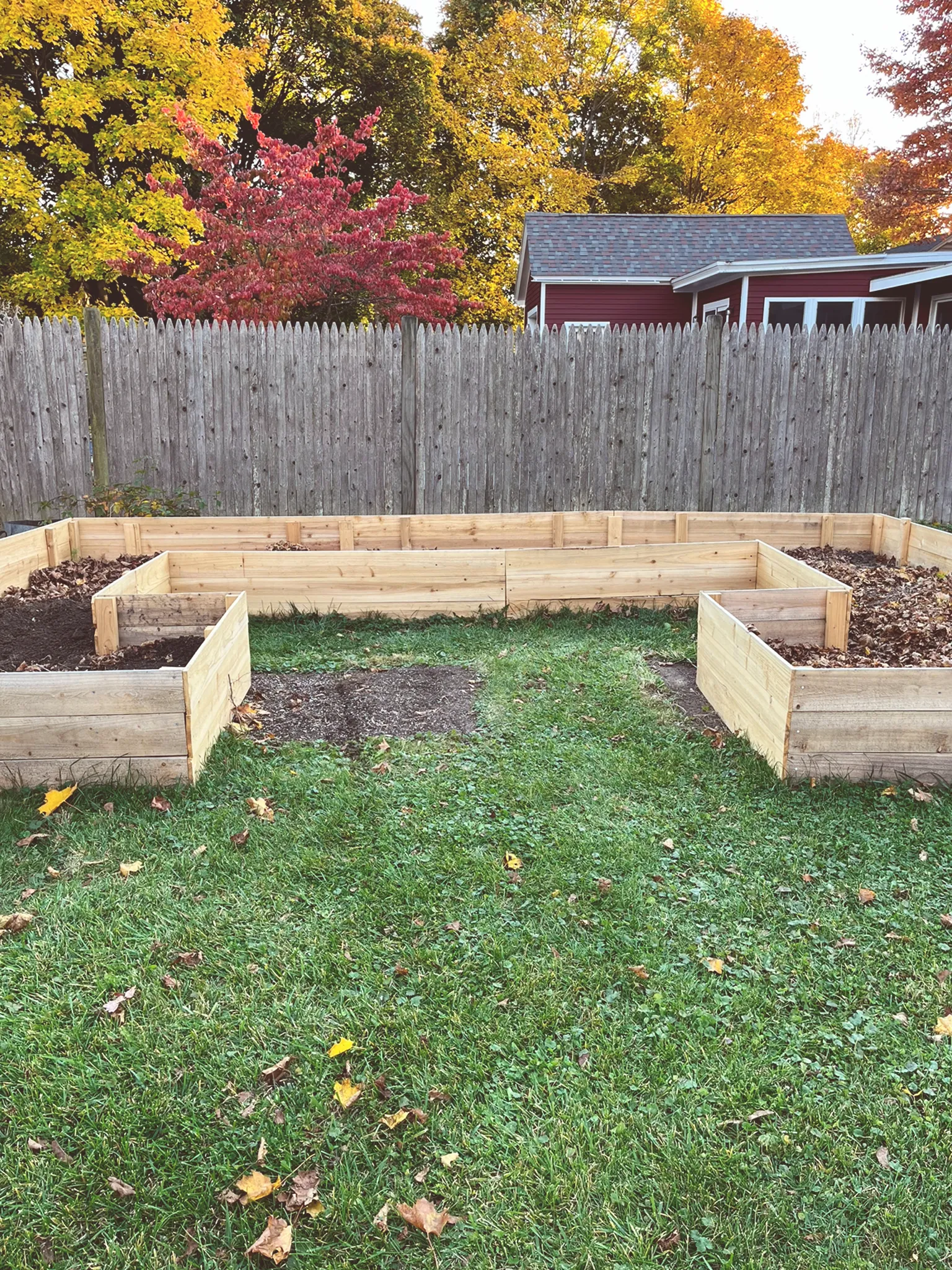 Front view of new raised bed filled halfway with leaves and soil. 