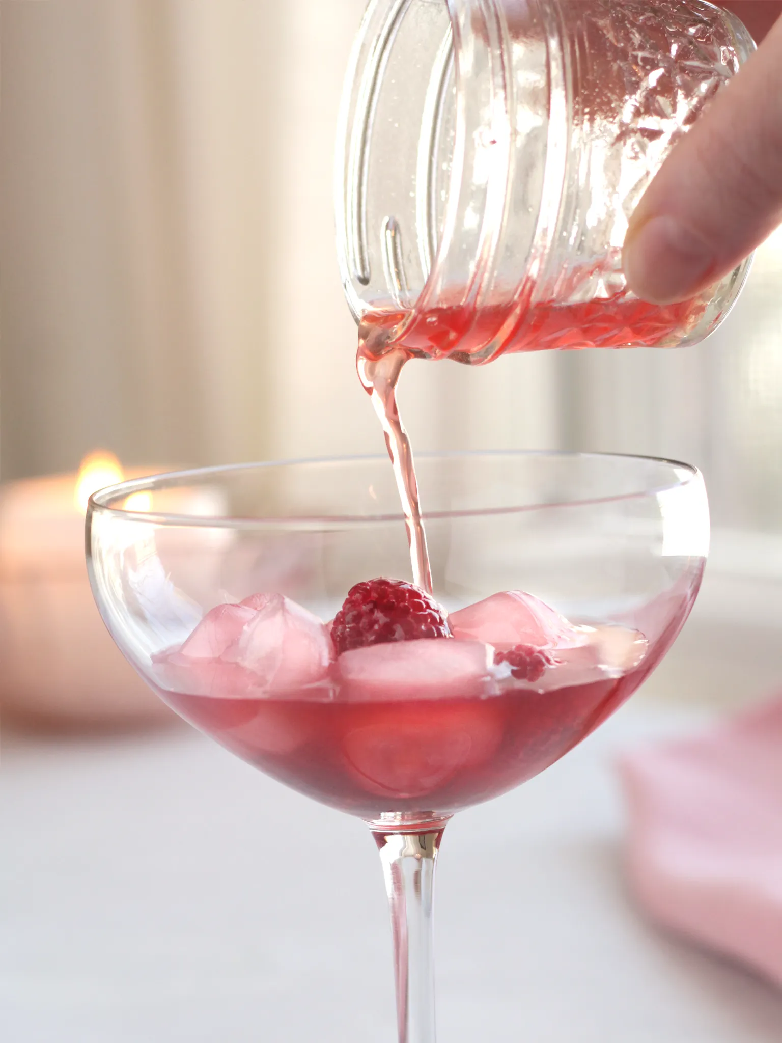 A Champagne coupe being filled with rose hawthorn berry shrub