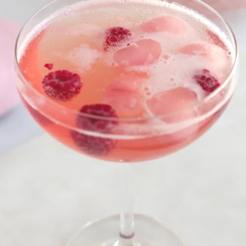 A Champagne coupe filled with rose hawthorn berry shrub mocktail