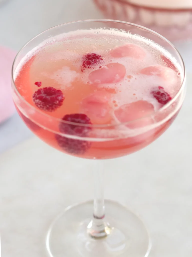 A Champagne coupe filled with rose hawthorn berry shrub mocktail